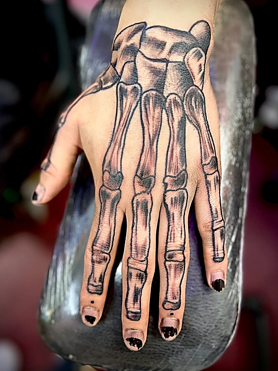 Tatuaje en el dorso de la mano: los huesos del esqueleto de la mano en negro y gris.